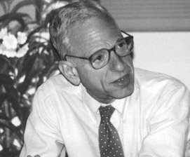 James L. Weil, a 60-ish man wearing glasses, a white dress short and tie, with a serious facial expression, likely discussing books and poetry with colleagues